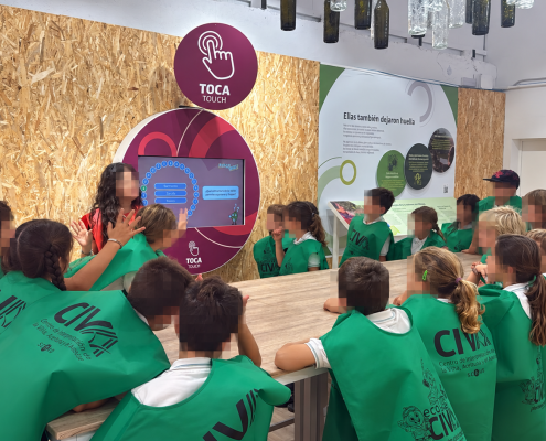 Visita escolar al museo interactivo Escolares tocan una pantalla interactiva sobre el aceite de orujo de oliva en el museo interactivo del CIVA