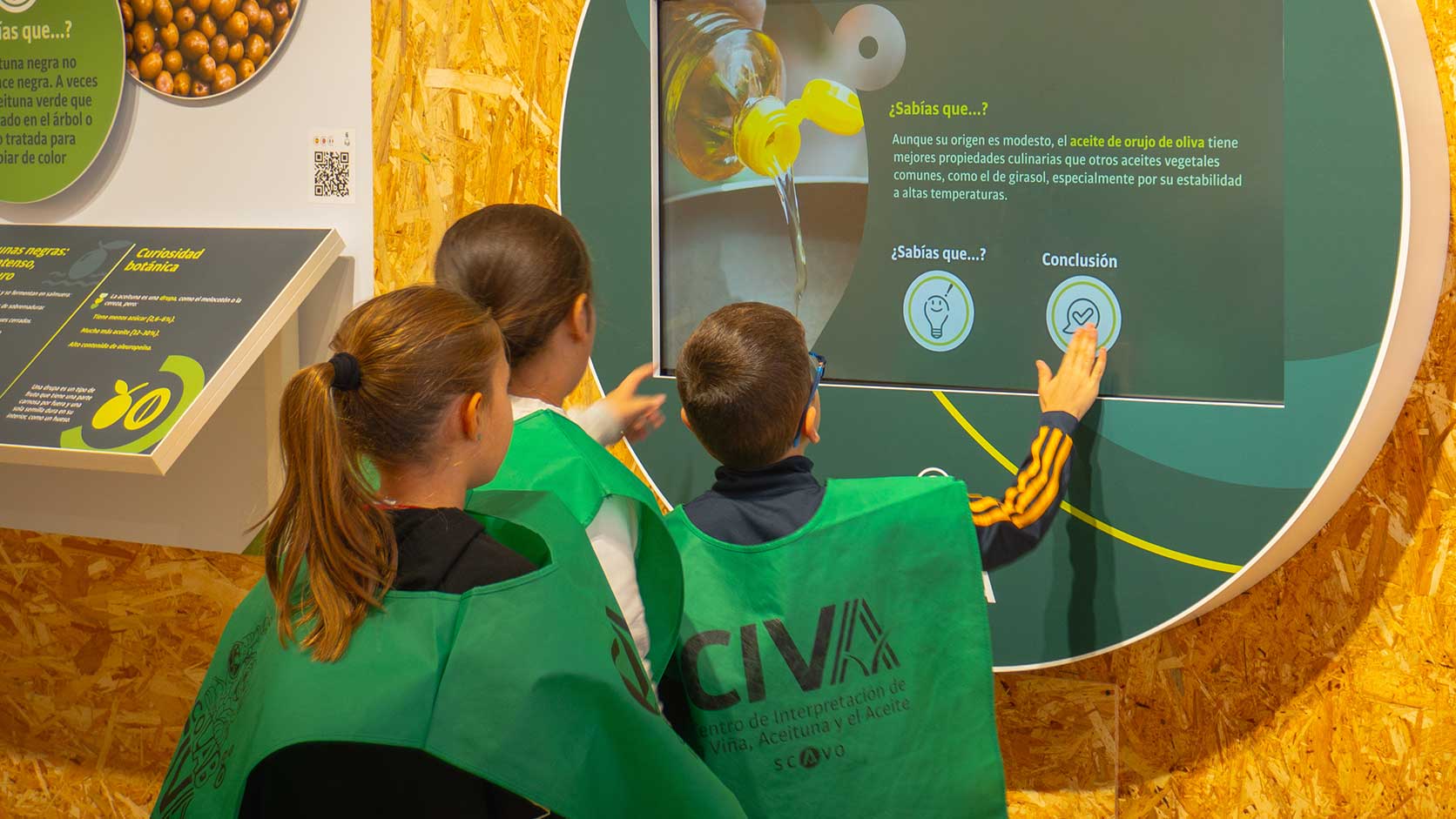Visita-escolar-al-museo-interactivo Un monitor explica a los escolares el panel de la Feria de la Vendimia de Mollina en el CIVA